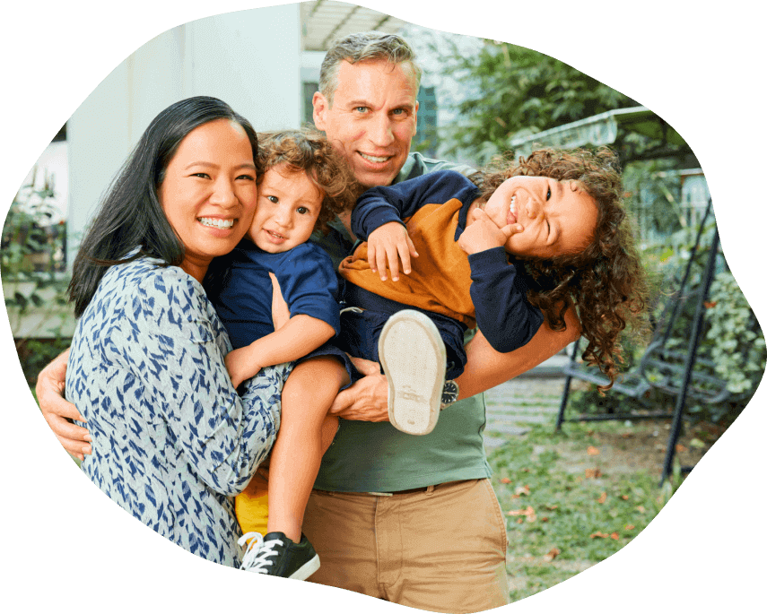 A mum and dad with two kids smiling and having fun, looking towards the camera